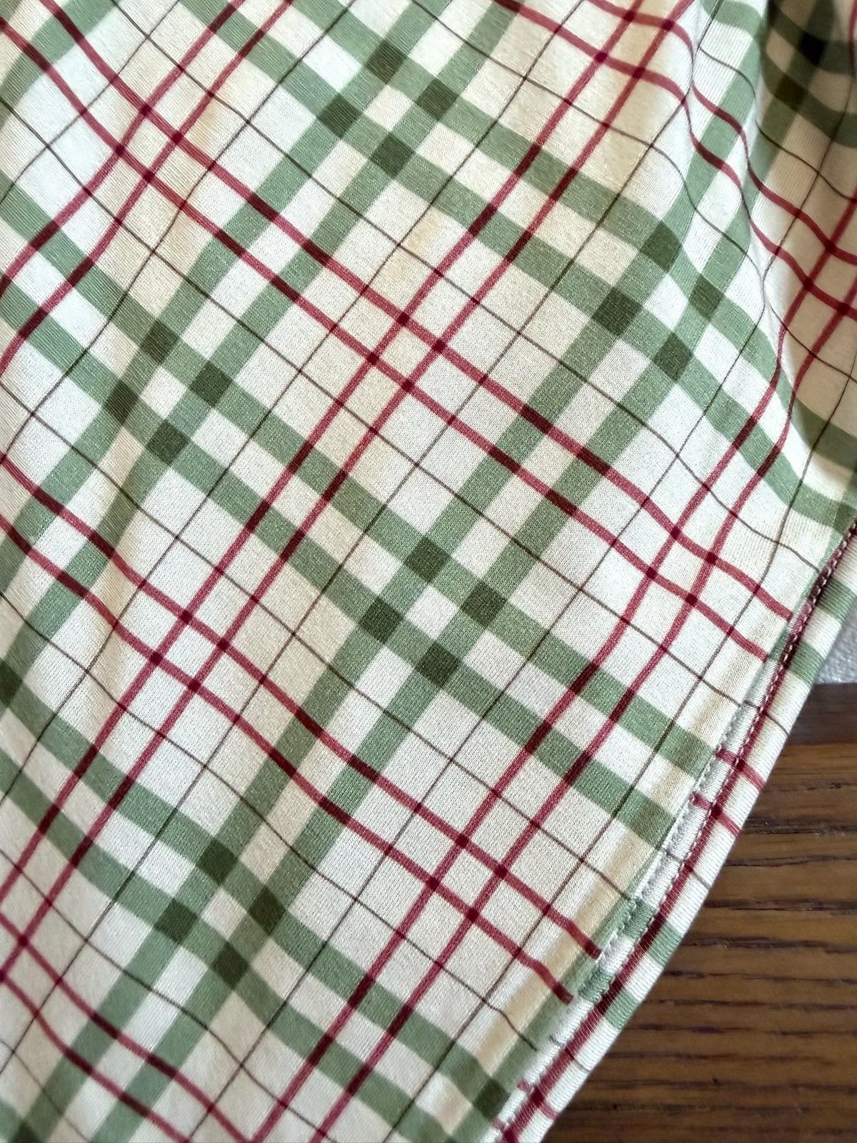 The homestead is a luxurious bamboo blanket featuring a red, dark green, and white plaid pattern with a hemmed edge.