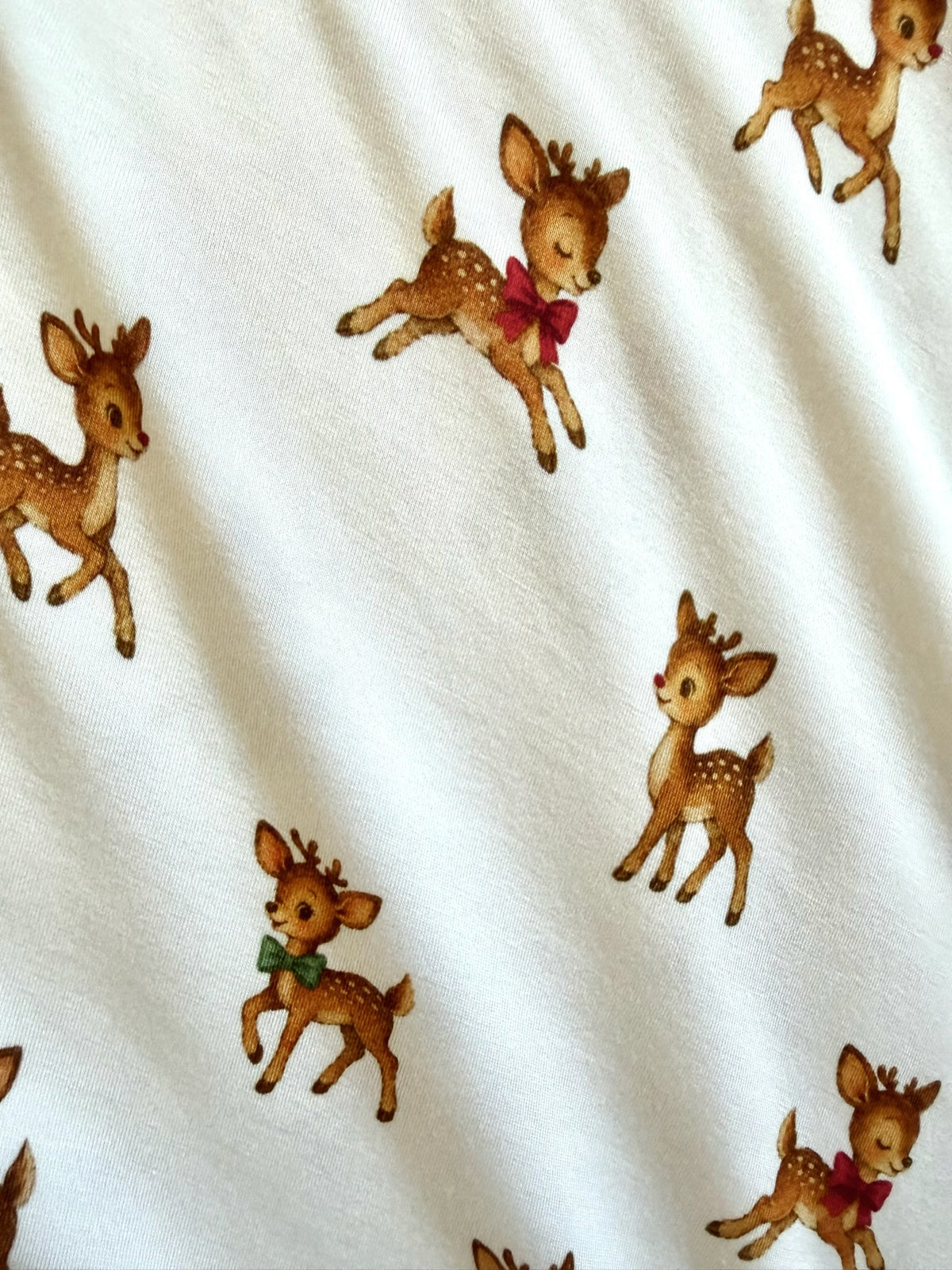 White bamboo vintage reindeer blanket patterned with illustrations of small fawns wearing red or green bow ties.
