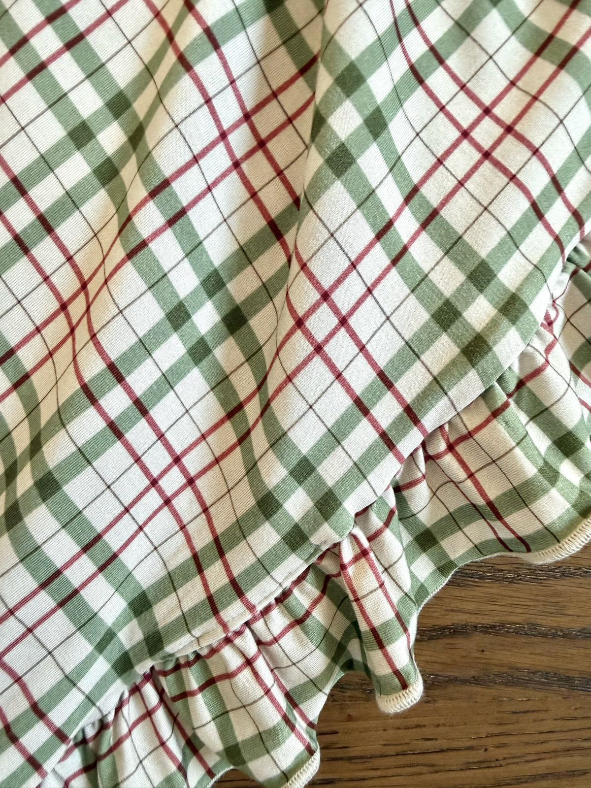 A luxurious homestead / ruffle plaid blanket in white fabric with a green and red pattern, finished with a gathered ruffle along the edge.