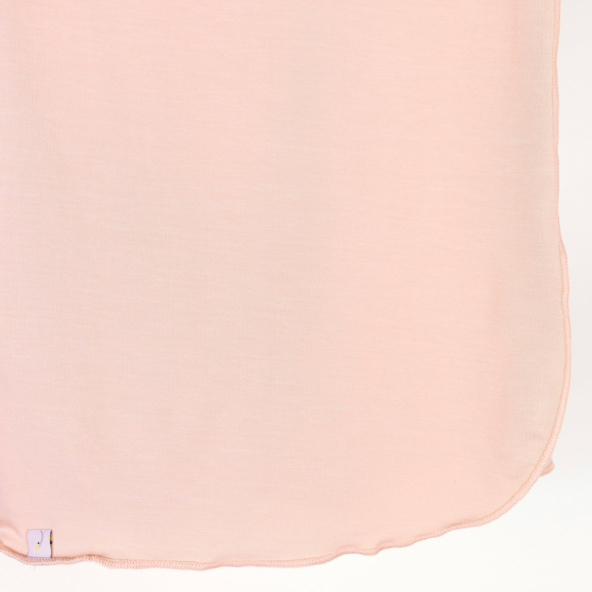 A single-layer whisp / swaddle in light pink, crafted from soft fabric with rounded edges and a small white tag at the bottom left corner, displayed on a plain white background.