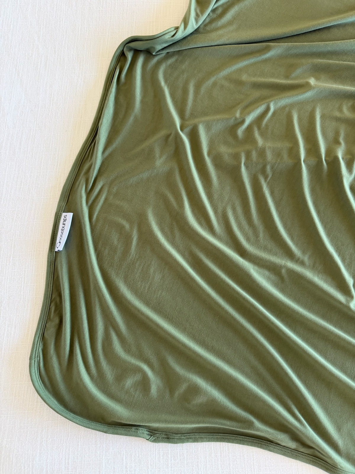 Winter pine olive green bamboo blanket with a stitched edge and a small brand tag.