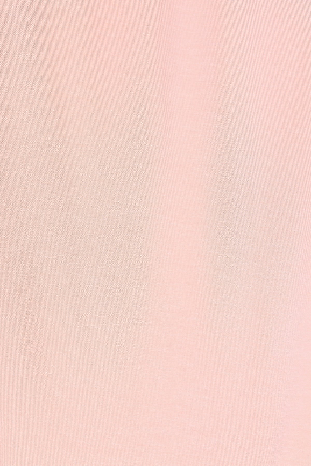 A close-up of the whisp / swaddle reveals its soft, light pink fabric with a smooth texture. Subtle shadows and gentle variations in color enhance the delicate and airy look of this single-layered swaddle.