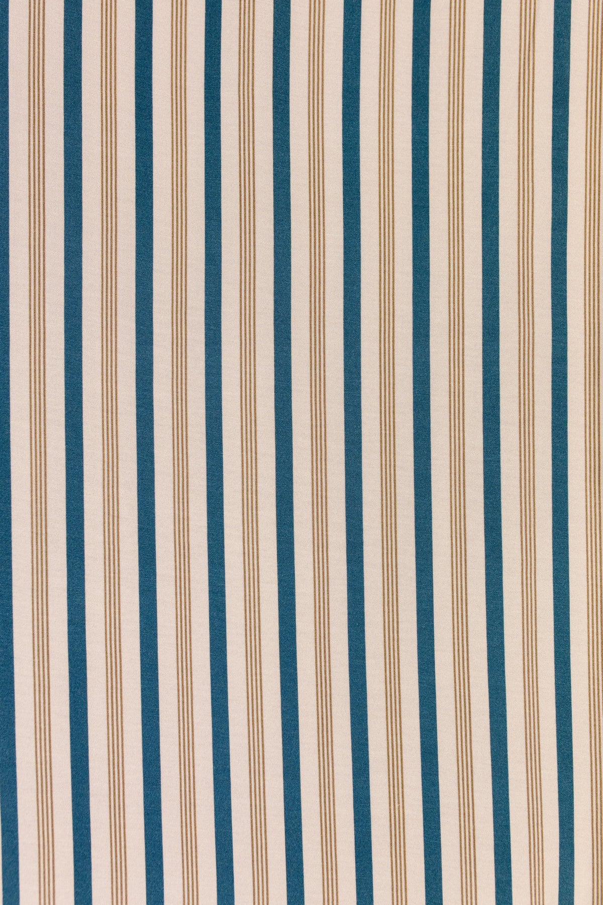 Shoreline / swaddle features blue and beige vertical stripes of varying widths, inspired by a tan and indigo stripe, adorning the fabric or wallpaper surface with a simple, repetitive striped pattern.