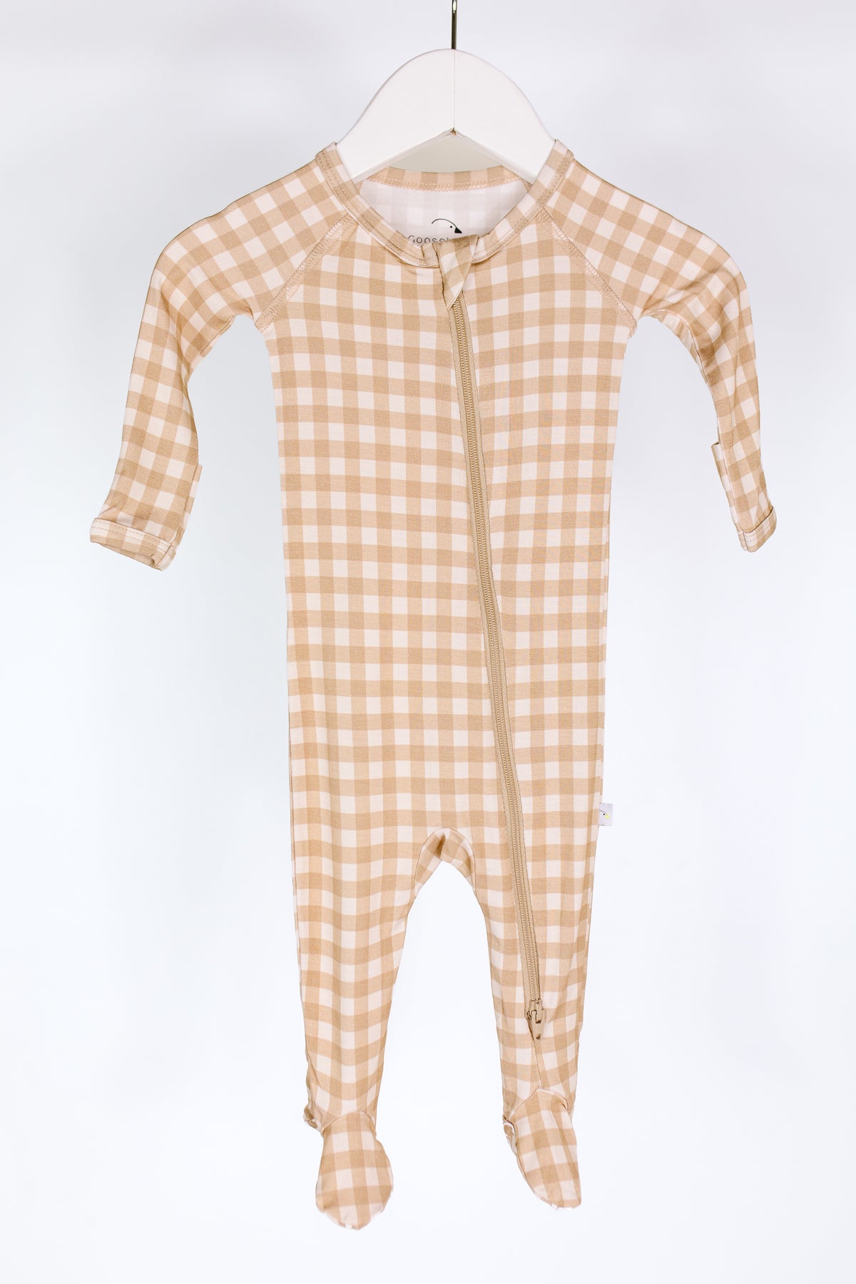 Teddy Bear Check one piece zipper, featuring a tan and white checkered bamboo fabric, long sleeves, and covered feet. Displayed on a white hanger against a white background, this newborn zipper onesie combines style and convenience with its diagonal zipper running from the neckline to the left ankle.