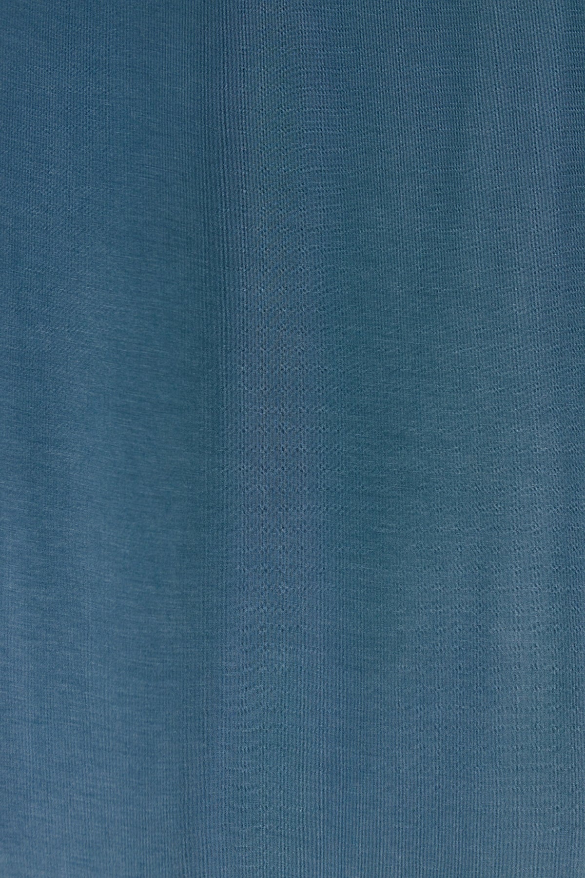 A close-up view of the tidal wave / swaddle fabric in indigo blue, featuring subtle vertical lines and a gentle, soft texture with slight variations in shading across the surface.
