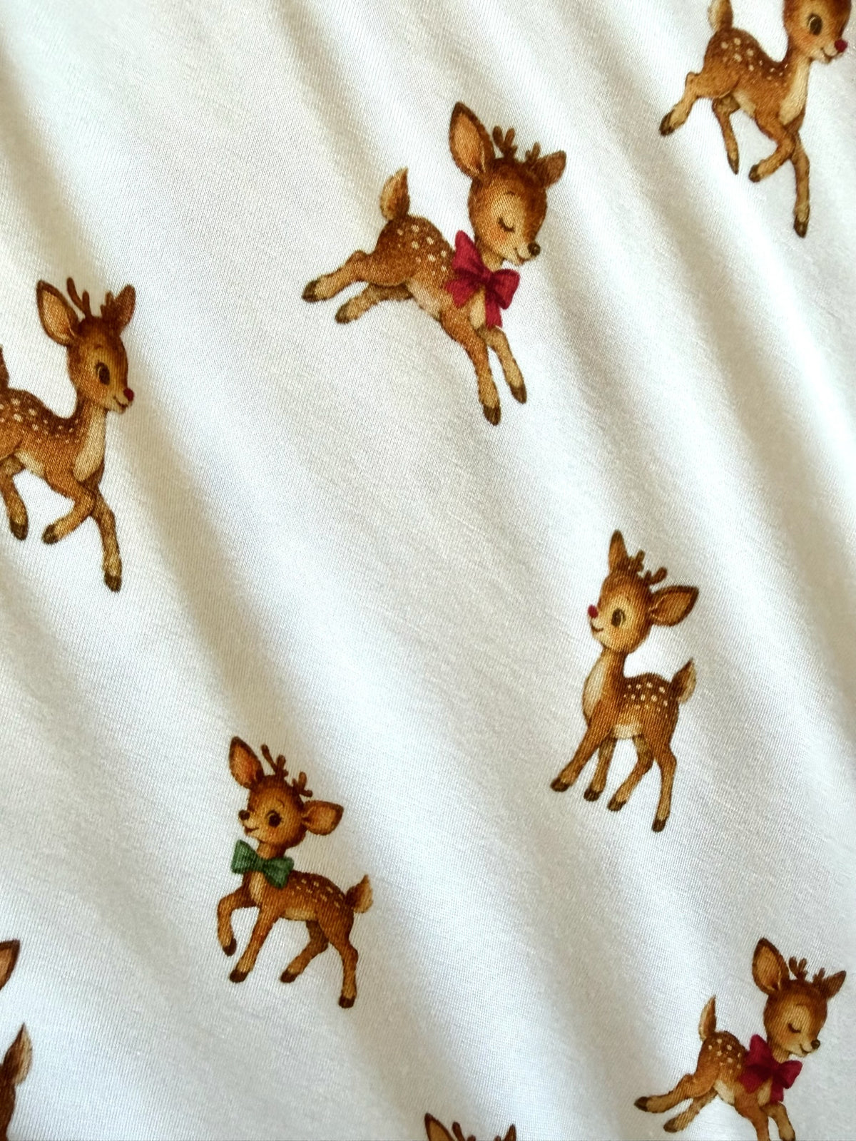 White bamboo vintage reindeer / one piece zipper sleeper patterned with illustrations of fawns wearing small red or green bows.