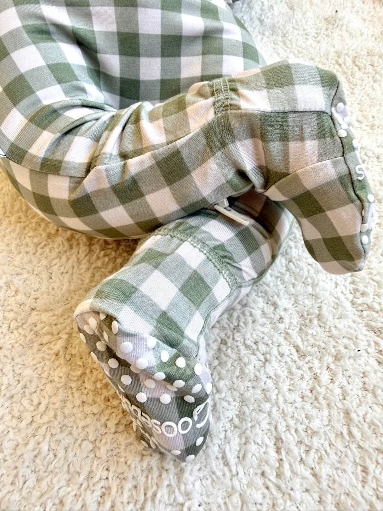 Baby wearing an evergreen lane / one piece zipper in sage green and white gingham with white non-slip grips on the soles.