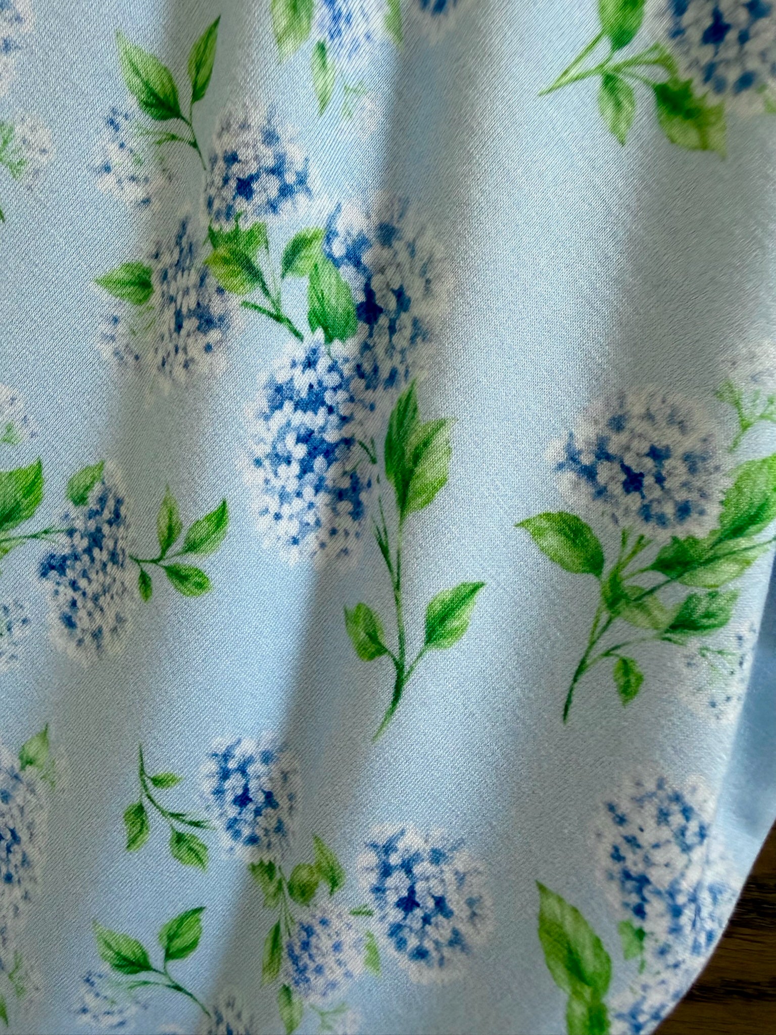 Crafted from bamboo in a light blue shade, the hydrangea blanket from the Goosebumps Collection features clusters of blue and white hydrangea flowers with green leaves scattered across the fabric. Perfect as an adult swaddle, it offers both comfort and style.