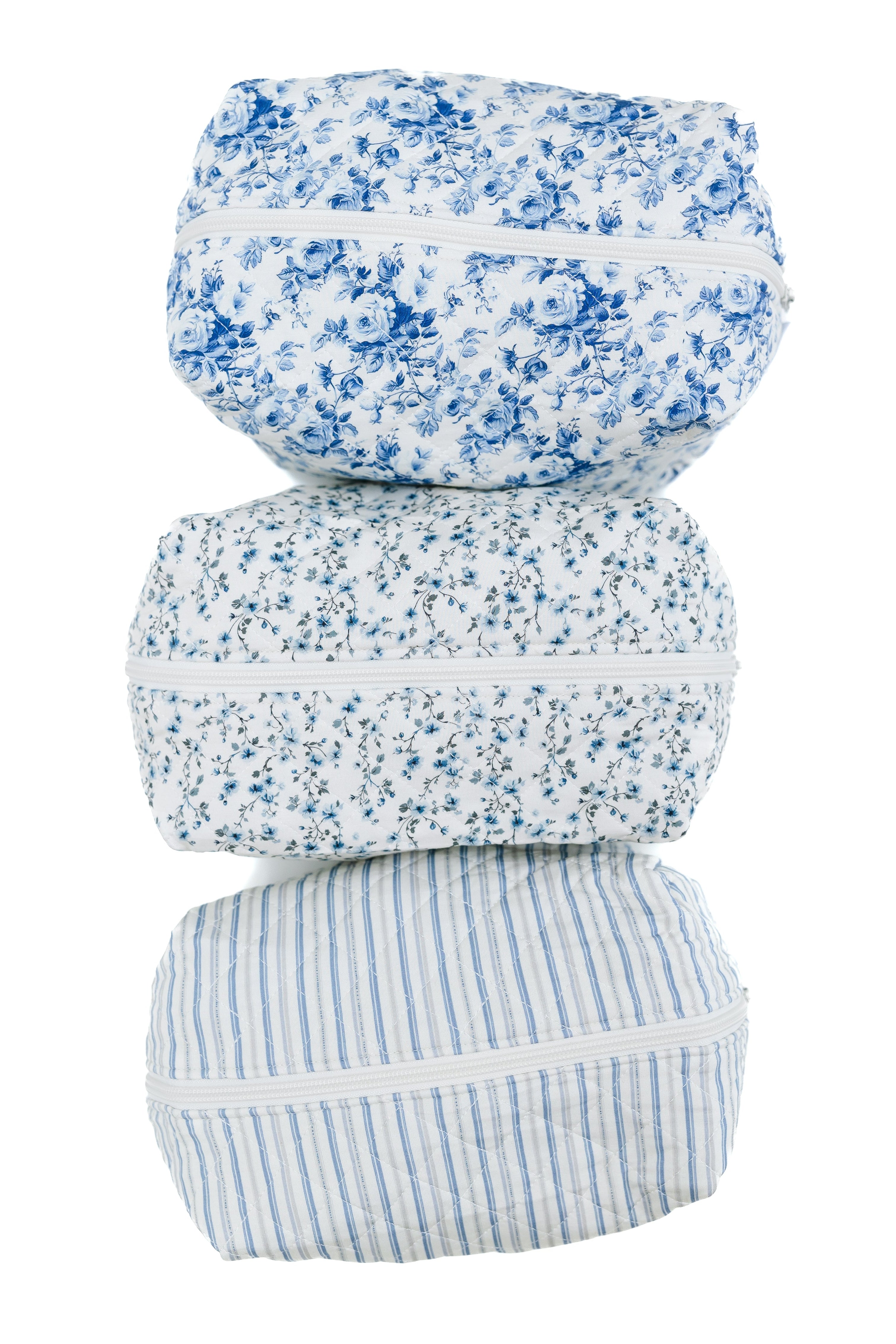 Blue haven / travel bag includes three vertically stacked fabric pouches, each with a unique blue-and-white Goosebumps-inspired pattern—floral, small floral, and vertical stripes. Each zippered pouch is perfect for stylish travel organization.