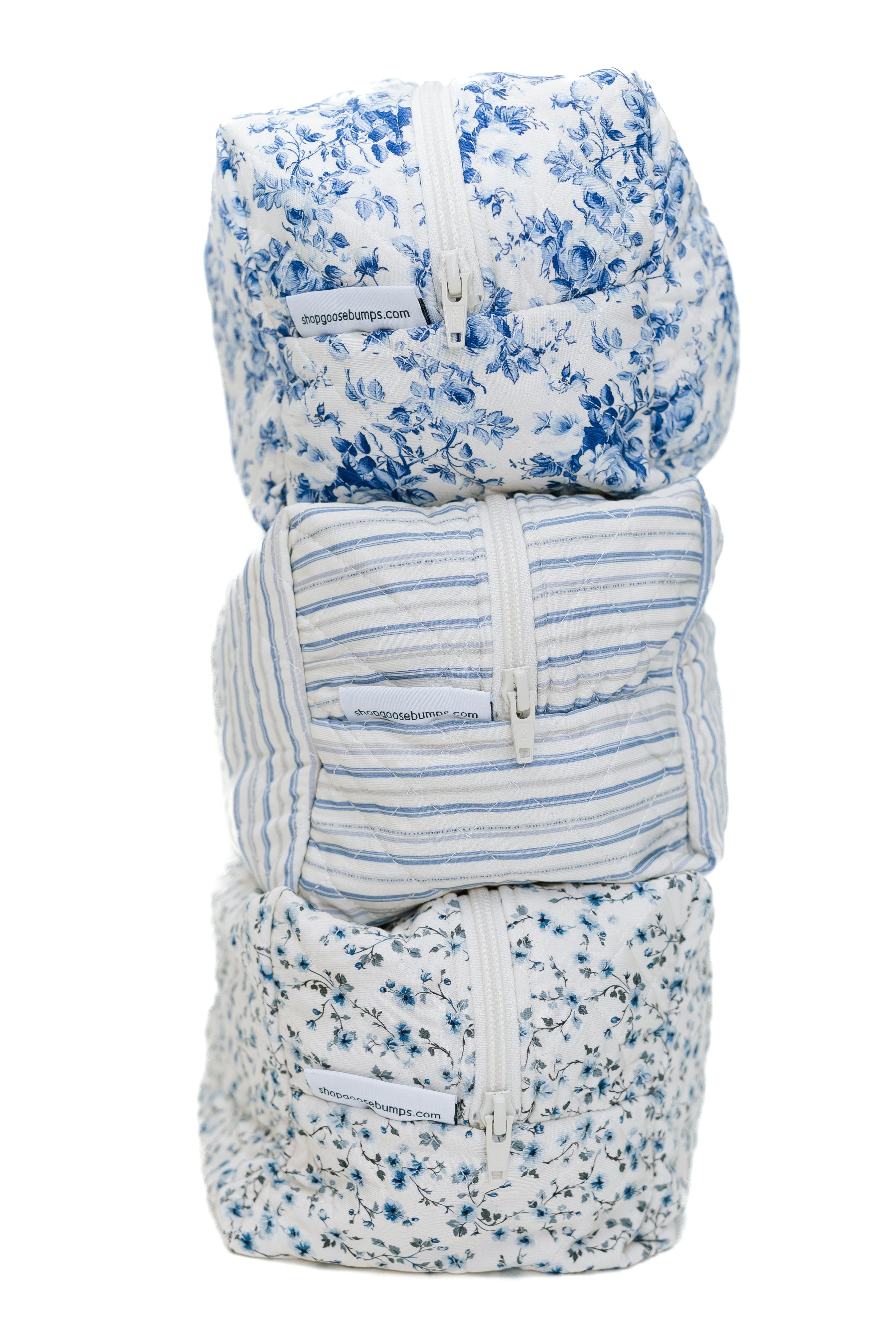 The blue haven / travel bag set features three soft, zippered pouches with blue and white Goosebumps prints—floral and striped—stacked vertically against a white background for a stylish, organized travel solution.