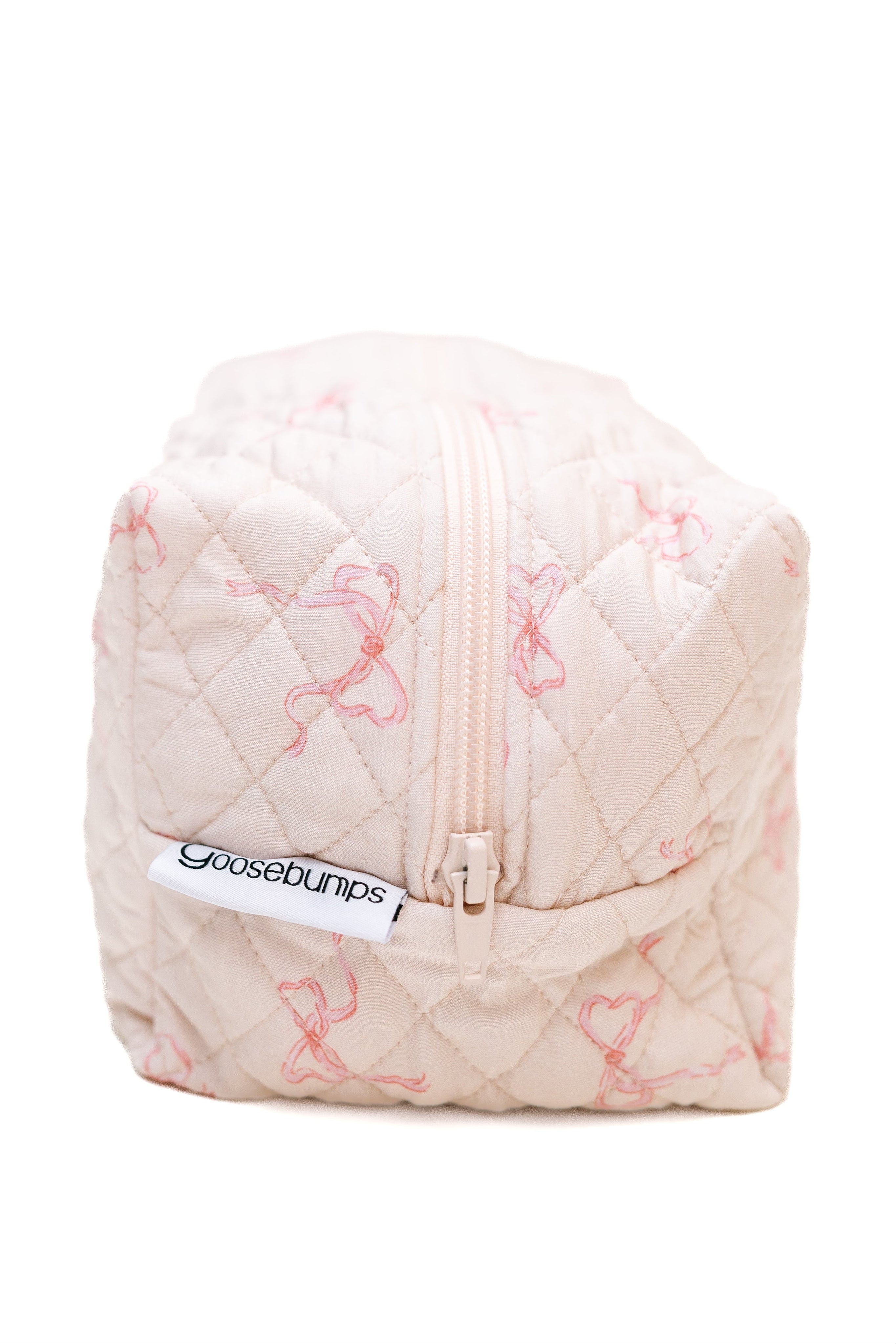 The ballerina / travel bag is a quilted, rectangular light pink pouch with a zipper and Goosebumps tag, featuring a subtle pink bow pattern—ideal for organizing travel accessories. Shown against a white background.