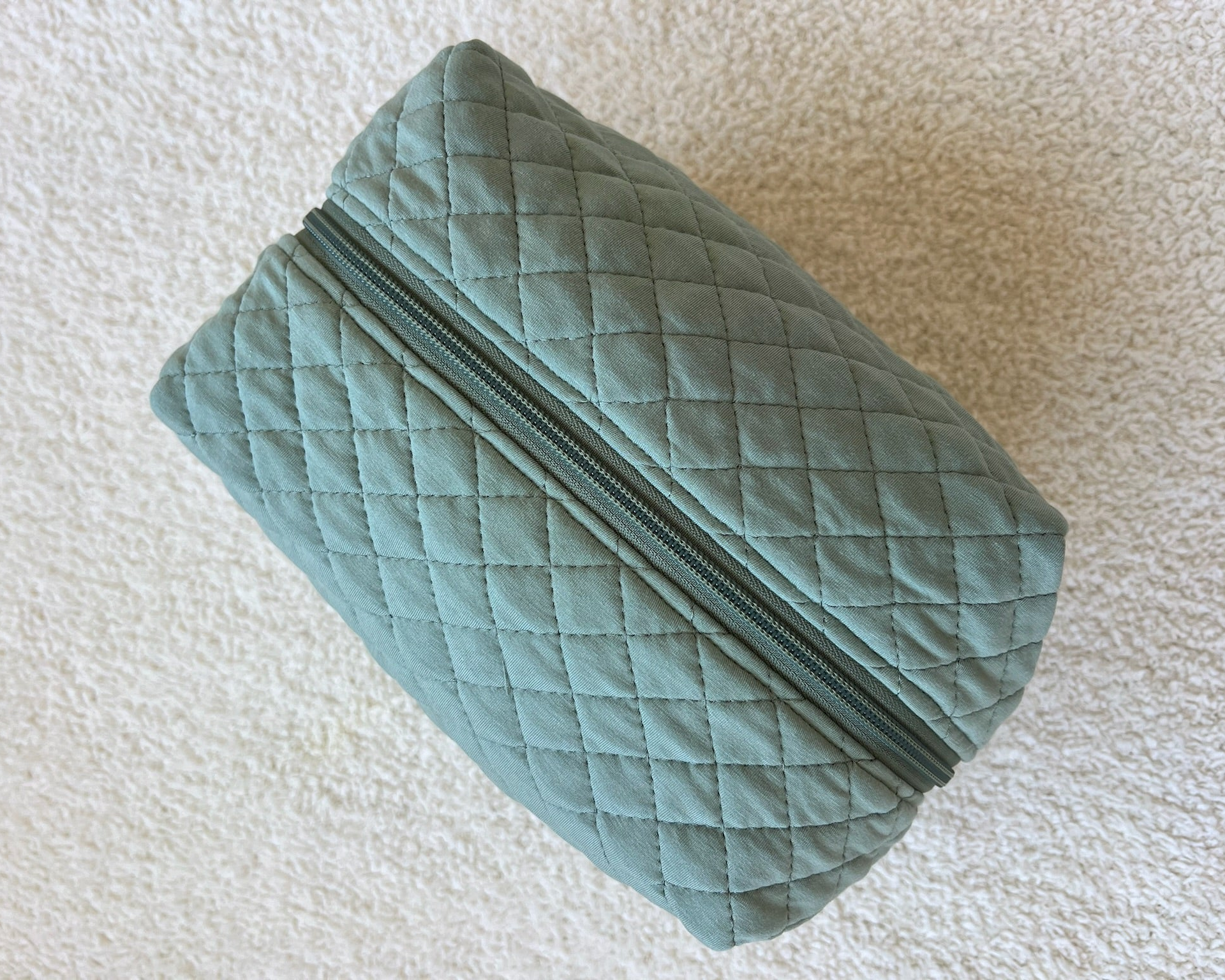 The basil / travel bag is a green quilted fabric travel bag with a zipper closure, ideal for organizing your travel accessories while on the go.