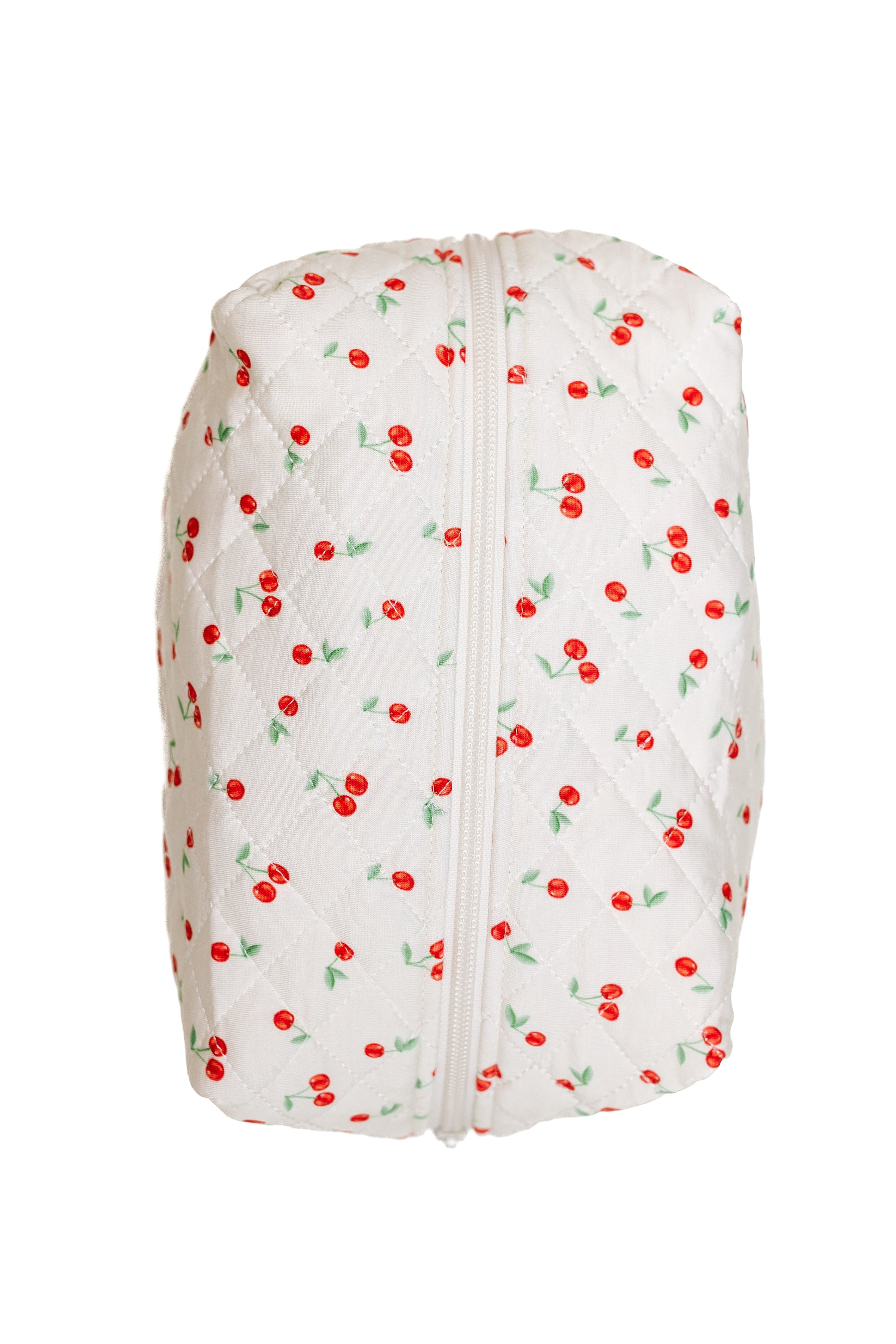 The cherry on top / travel bag is a white quilted pouch with a zipper, featuring a cute pattern of red cherries and green leaves—perfect for carrying your travel accessories in style.