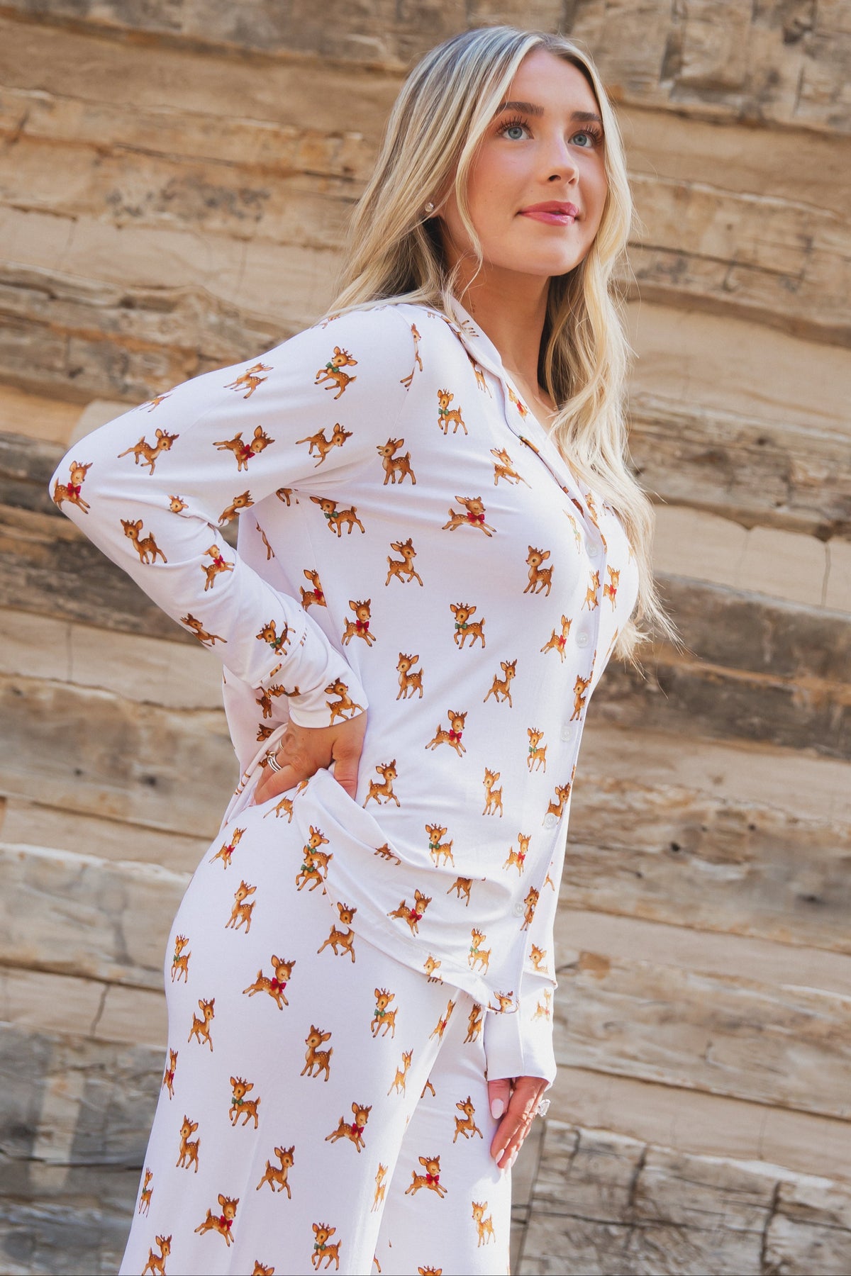 A person wearing a vintage reindeer pajama set with a long-sleeved button-up top and matching long pants.