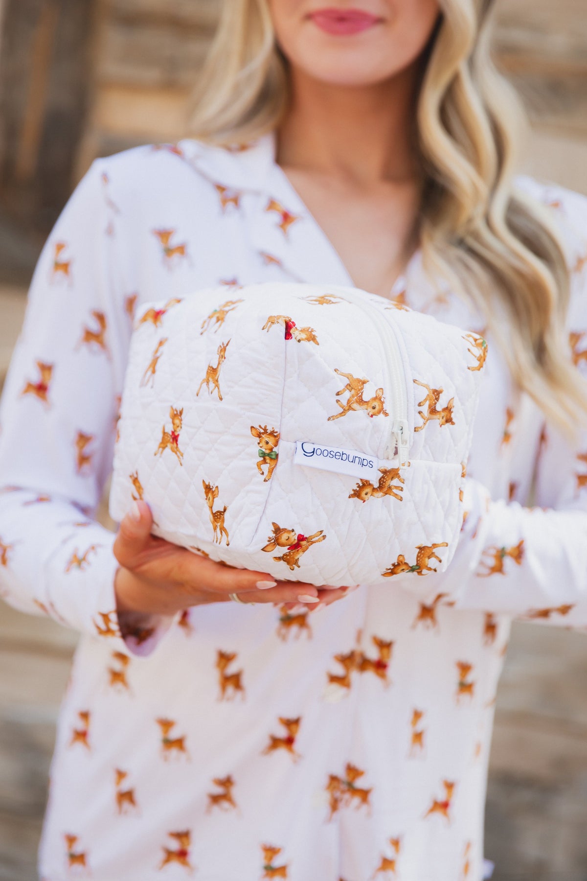 A person holds a quilted vintage reindeer / travel bag featuring a reindeer print.