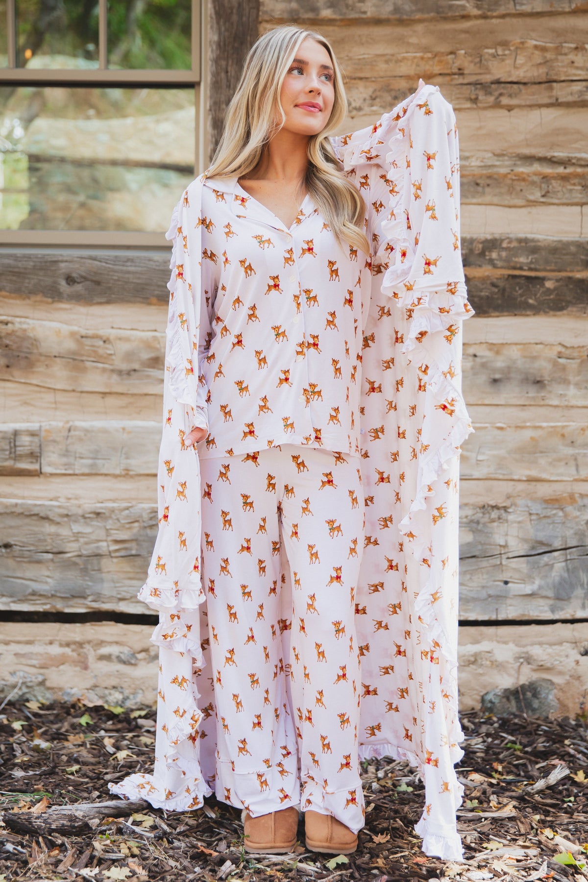 A person wearing a vintage reindeer / ruffle button-up pajama set with matching pants, holding a matching luxurious bamboo blanket around their shoulders.