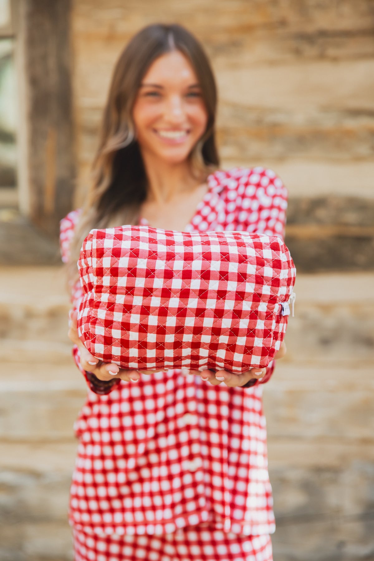 A person holding out a red and white gingham checkin’ it twice / travel bag.