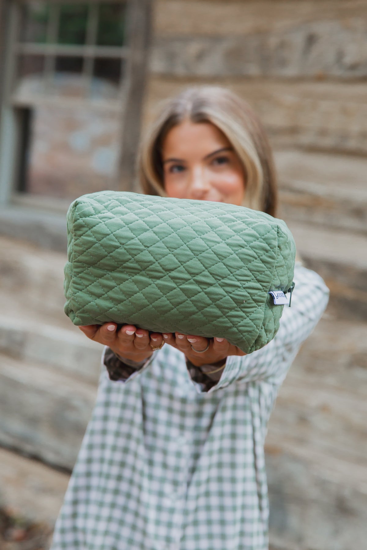 A person holds out a winter pine travel bag, a quilted olive green design made from bamboo viscose.