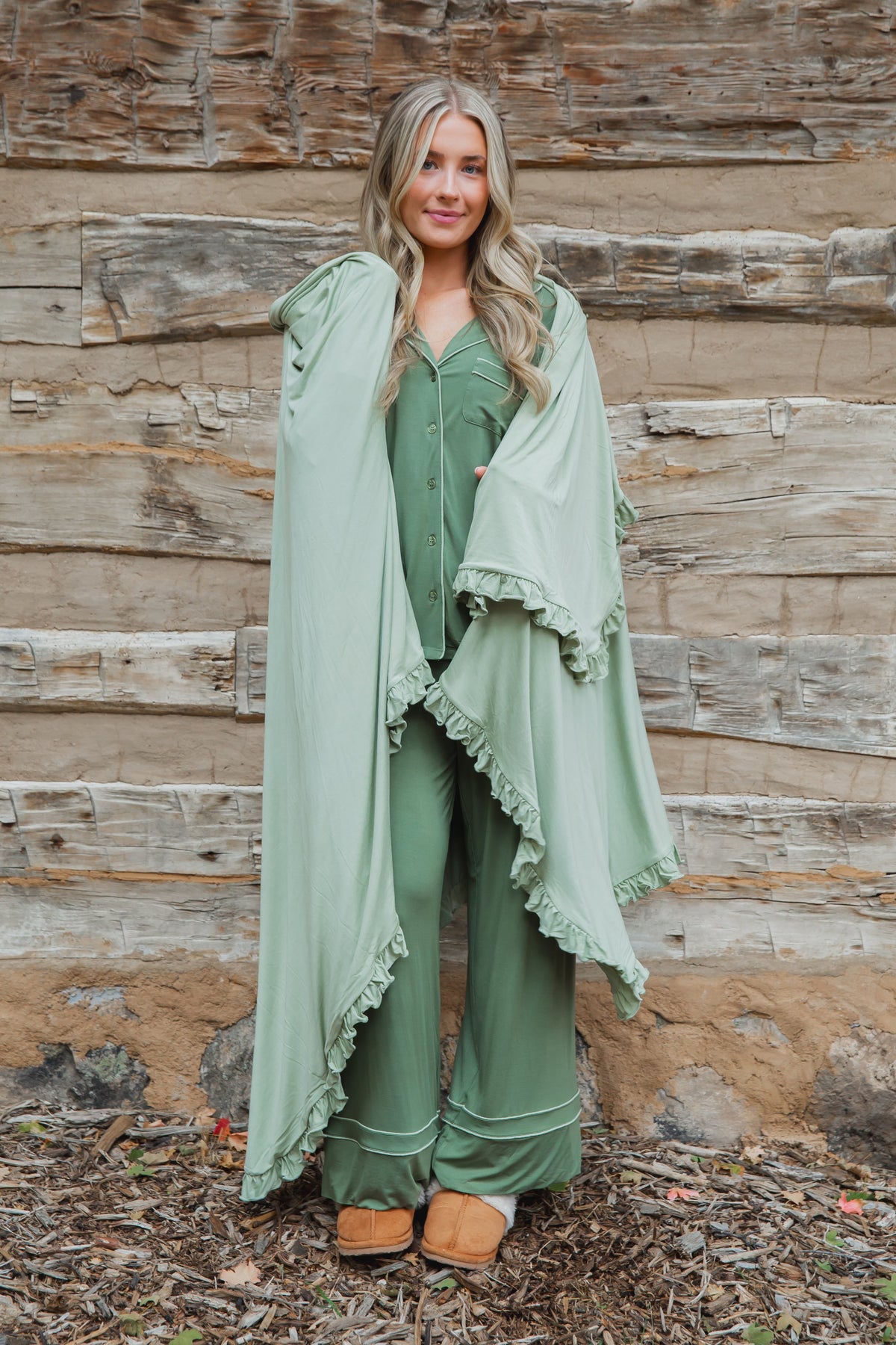 A woman wears frosted fir / ruffle bamboo pajamas and a matching hooded cape with ruffle trim.