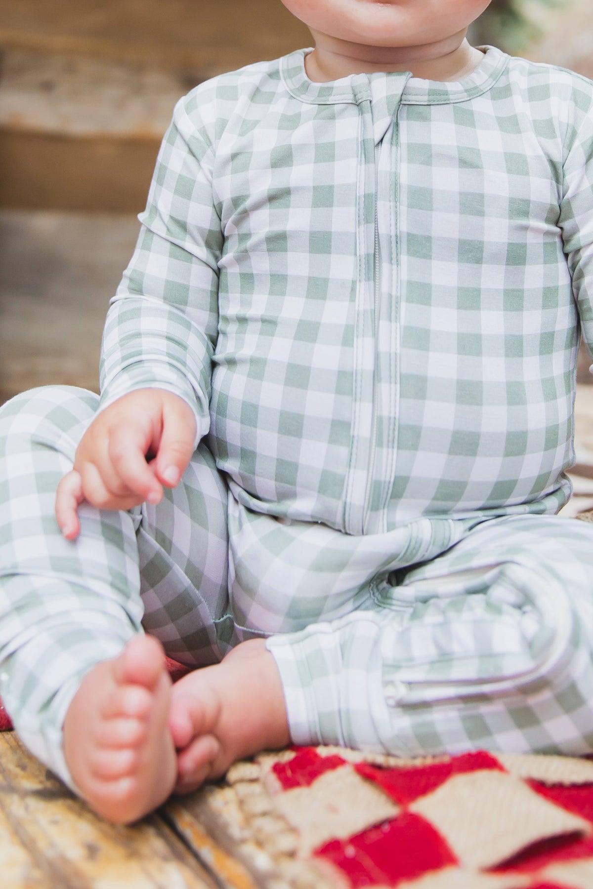 Newborn wearing an evergreen lane / one piece zipper in light green and white gingham with a front zipper.