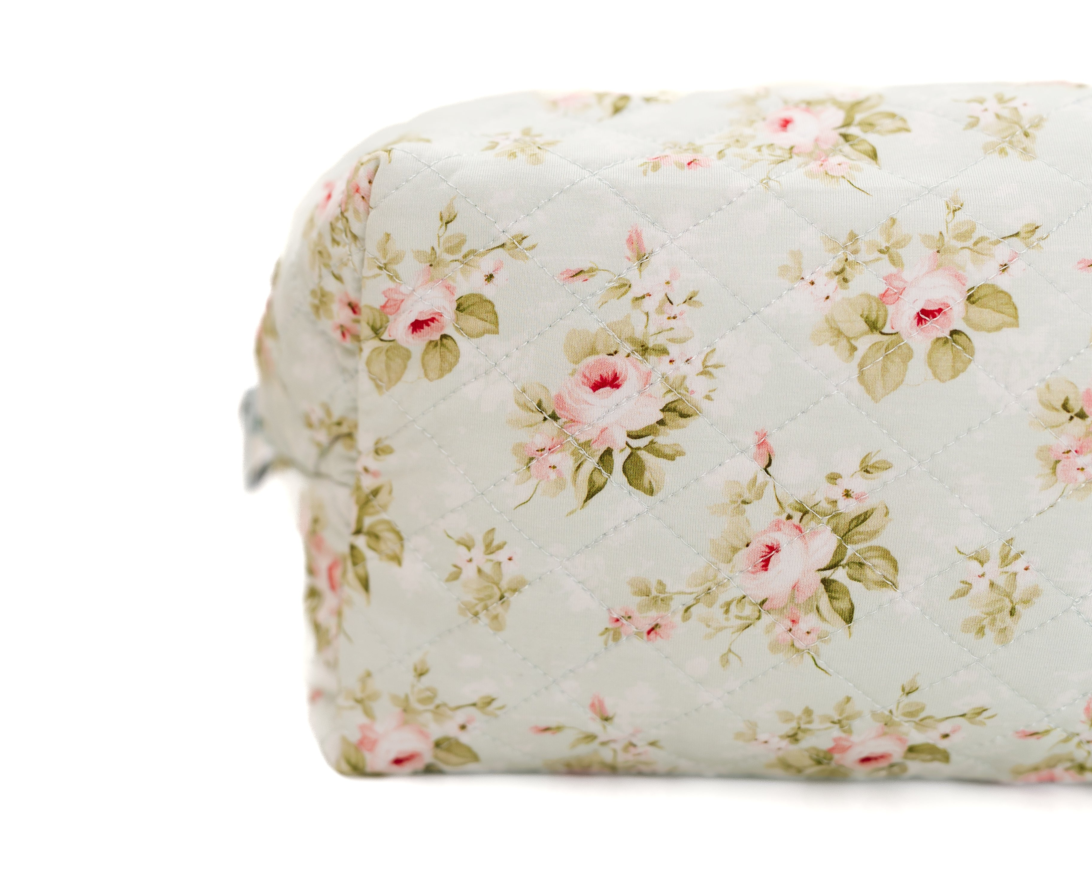The "mint to be" travel bag showcases a close-up of its quilted design, adorned with a delicate floral print featuring pink roses and green leaves on a light background.